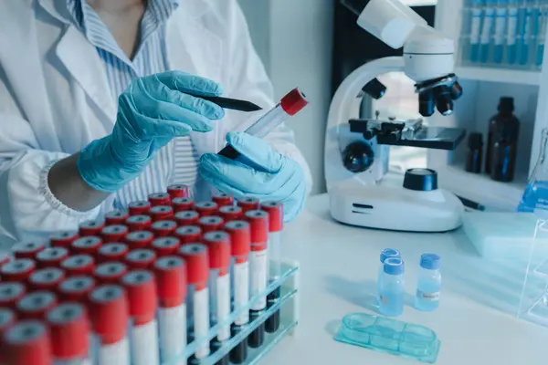 Kimyager kandaki kimyasalları araştırmak için mikroskop kullanıyor. Bilim adamı laboratuvarda kimyasallarla deney yapıyor. Kimyager test tüplerindeki kimyasalları kimyasal reaktörlerle ayırıyor.,
