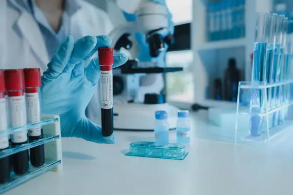 Kimyager kandaki kimyasalları araştırmak için mikroskop kullanıyor. Bilim adamı laboratuvarda kimyasallarla deney yapıyor. Kimyager test tüplerindeki kimyasalları kimyasal reaktörlerle ayırıyor.,