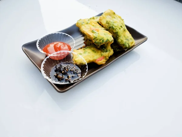 Tempe goreng ya da Tempe Mendoan, beyaz bir tabakta siyah bir kaseye izole edilmiş flüor hamuru, acı biber sosu ve soya sosuyla kaplı geleneksel Endonezya yemeğidir..