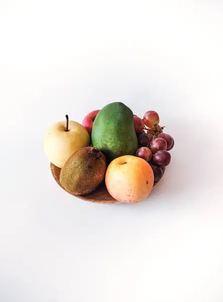 Bir sürü elma, armut, kivi meyvesi, mango ve üzüm beyaz arka planda ahşap bir tabakta, makale, metin ve meyve suyu tarifi amacıyla..