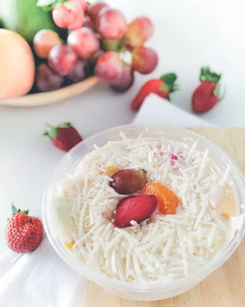 Beyaz arka planda rendelenmiş ev yapımı peynirli taze meyve salatası..