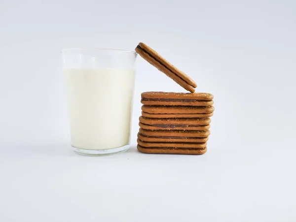 Beyaz arka planda izole edilmiş çikolata kremalı bisküviler ve bir bardak süt.