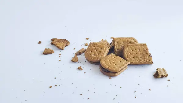 Çikolata kremalı bisküviler beyaz bir arka planda bazı kırıntılar, gevrek tatlı yiyecekler ve yararlı kurabiyeler dolduruyor..