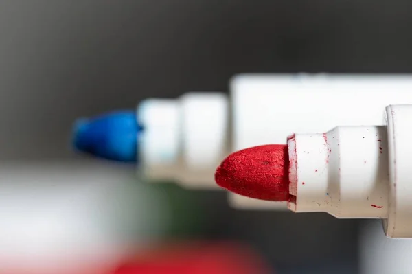 Extreme close up of the tip of a red felt-tip pen in the foreground and another blurred blue one behind