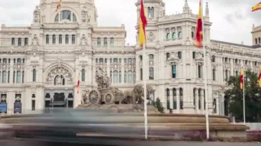 Madrid, İspanya; 10-16-2023: Plaza de Cibeles 'deki heykelde aynı adı taşıyan tanrıça ve rüzgarda sallanan İspanyol bayraklı iki aslanın temsili ile zaman aşımı