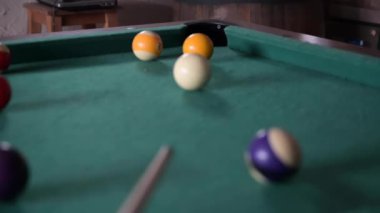Beyaz bir bilardo topunun diğer toplarla çevrili sarı bir topa ve havuz cebine vuruşunu gösteren 4K yavaş çekim videosu.