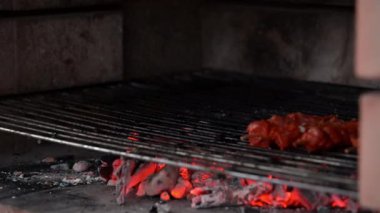 Kömürde pişirmek için mangalın üzerine marine edilmiş domuz pirzolası ve tavuk şişi koyan adam.