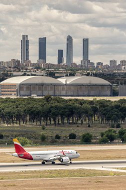 Madrid, İspanya; 05-18-2024: İspanya 'nın Iberia havaalanına iniş yapan İberya Airbus A320 modelinin ticari uçağı, iş alanının beş kulesiyle birlikte Madrid' e indi.