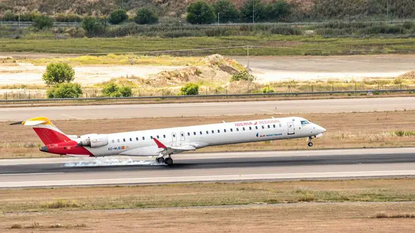 stock image Madrid, Spain; 05-18-2024: Commercial airplane of the CRJ-1000 model of the Spanish company Air Nostrum landing on the runway causing smoke when the landing gear makes contact with the asphalt