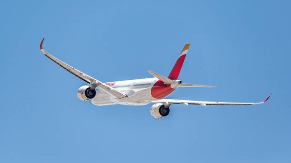 Мадрид, Испания; 05-24-2024: Крупный угловой снимок самолета Airbus A350 от испанской компании Iberia, замеченного снизу, который завершает взлётный маневр, набирая высоту