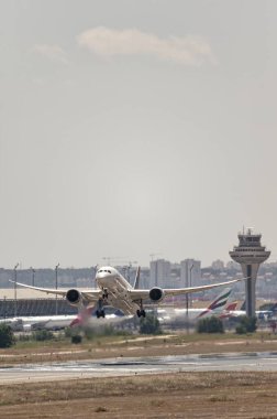 Madrid, İspanya; 05-24-2024: Boeing 787 model Şili modeli uçak kalkış manevrasına iniş takımlarının açılmasıyla ve havaalanı kontrol kulesinin arkasından başlıyor