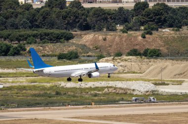 Boeing 737 modelinin ticari uçağı koyu mavi flapları ve kuyruğu iniş takımlarını giyip piste yaklaşmaya hazırlanıyor.