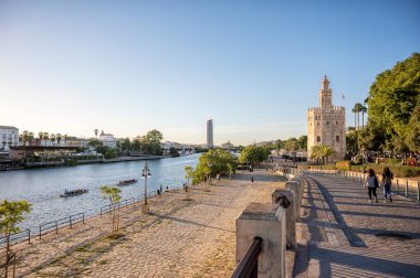 Sevilla, İspanya; 10-24-2024: 16. Alfonso Kanalı veya Guadalquivir havzası Seville 'deki ünlü Torre del Oro' nun yanından geçerken turist botları kenetlenmiştir.