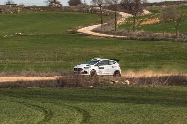 Madrid, İspanya; 02-15-2025: İspanya 'nın Alcarria Madrilena Rallisi' nde hız yapan beyaz Ford Fiesta ralli aracı. Heyecan verici bir motor sporu çekimi hız, toz ve hassas sürüş