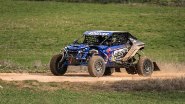 Madrid, İspanya; 02-15-2025: Can-Am Maverick X3 at arabası toprak yolda hızlanıyor, çevik manevraları ve toz izleri off-road yarışlarının maceracı ruhunu vurguluyor