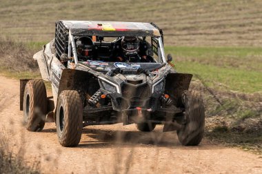 Madrid, İspanya; 02-15-2025: Can-Am Maverick X3 at arabası toprak yolda hızlanıyor, çevik manevraları ve toz izleri off-road yarışlarının maceracı ruhunu vurguluyor