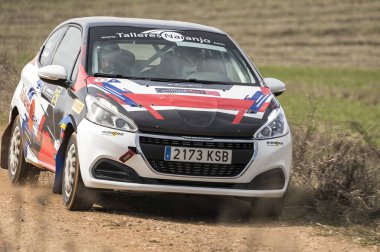 Madrid, İspanya; 02-15-2025: Peugeot 208 Puretech 1.2 T N3 toprak yolda hızlanıyor, dinamik hareketi ve toz bulutu rali yarışmasının ham yoğunluğunu yansıtıyor