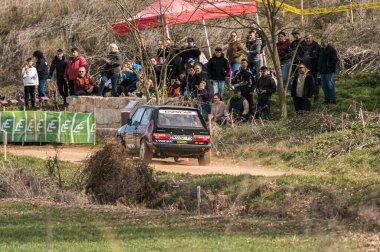 Madrid, İspanya; 02-15-2025: Volkswagen Golf ralli arabası keskin bir virajda sürükleniyor ve izleyiciler izlerken toprağı tekmeliyor. Yoğun bir off-road yarışında yüksek hızlı motor sporu eylemi