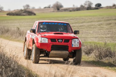 Madrid, İspanya; 02-15-2025: Kızıl Nissan Navara kamyonu engebeli bir rali baskını, toz püskürtme ve off-road pistinde güç ve dayanıklılık gösterisi yoluyla saldırıyor