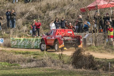 Madrid, İspanya; 02-15-2025: Nissan Navara rali kamyonu dar bir virajdan güç alarak, izleyiciler izlerken toz topluyor. Off-road motor sporu yarışı en iyi performansını sergiliyor.