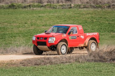 Madrid, İspanya; 02-15-2025: Kızıl Nissan Navara kamyonu engebeli bir rali baskını, toz püskürtme ve off-road pistinde güç ve dayanıklılık gösterisi yoluyla saldırıyor