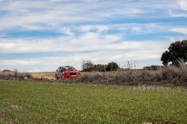 Madrid, İspanya; 02-15-2025: Bir BMW 325i E30 serisi rali arabası bir çakıl mitinginin bir safhasında bir bahar günü kırsal bir pistte sürüyor.