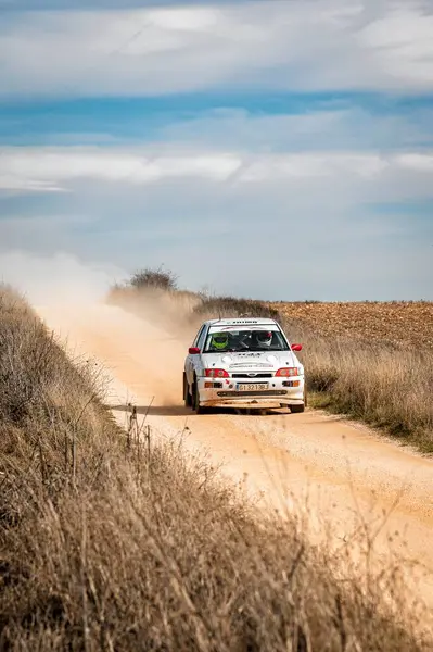 Madrid, İspanya; 02-15-2025: Ford Escort RS Corsworth, yoğun mavi gökyüzü olan bir günde toprak yolda ilerleyen ve toz kaldıran klasik bir araç