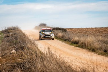 Madrid, İspanya; 02-15-2025: Toyota Aygo N3 rali arabası açık gökyüzünün altında tozlu bir pistte roket atarak yoğun bir off-road motorsporu yarışında bulutları tekmeledi
