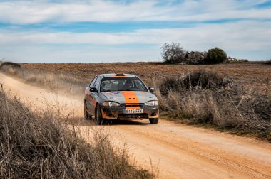 Madrid, İspanya; 02-15-2025: Bir Hyundai Accent ralli arabası tozlu bir pistte kararlılıkla dalgalanarak, heyecan verici bir off-road motor sporu yarışmasında toz bulutlarını tekmeledi