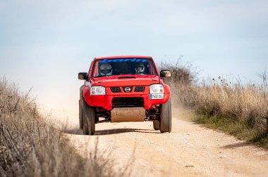 Madrid, İspanya; 02-15-2025: Kızıl Nissan Navara kamyonu engebeli bir rali baskını, toz püskürtme ve off-road pistinde güç ve dayanıklılık gösterisi yoluyla saldırıyor