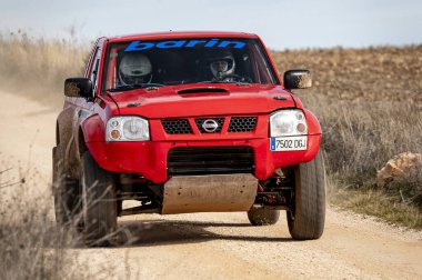 Madrid, İspanya; 02-15-2025: Kızıl Nissan Navara kamyonu engebeli bir rali baskını, toz püskürtme ve off-road pistinde güç ve dayanıklılık gösterisi yoluyla saldırıyor