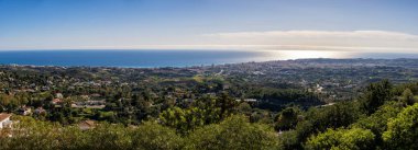 İspanya 'nın Mlaga kentindeki Mijas gözcüsünden Akdeniz' in panoramik manzarası. Mavi sular ufuk çizgisiyle buluşuyor. Güneşli tepeler ve berrak gökyüzü tarafından çerçeveleniyor.