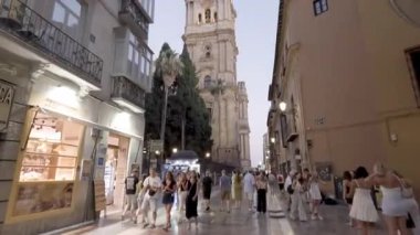Malaga, İspanya; 07 / 15 / 2025: Malaga sokaklarının tarihi kulesi, canlı atmosferi ve kültürel çekiciliğini sergileyen Malaga Katedrali yakınlarındaki turistlerle dolu 4K videosu