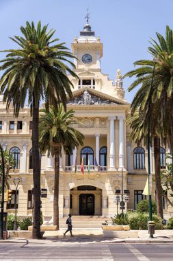 Malaga, İspanya; 07-15-2025: Paseo del Parque 'daki Malaga Belediye Binası' nın ana cephesi, önünde palmiye ağaçları, trafik ışığı ve yol ile İspanya 'nın Endülüs kentinde açık mavi bir gökyüzünün altında