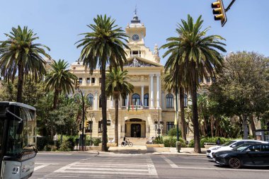 Malaga, İspanya; 07-15-2025: Paseo del Parque 'daki Malaga Belediye Binası' nın ana cephesi, önünde palmiye ağaçları, trafik ışığı ve yol ile İspanya 'nın Endülüs kentinde açık mavi bir gökyüzünün altında