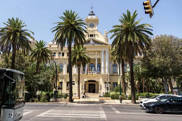 Malaga, İspanya; 07-15-2025: Paseo del Parque 'daki Malaga Belediye Binası' nın ana cephesi, önünde palmiye ağaçları, trafik ışığı ve yol ile İspanya 'nın Endülüs kentinde açık mavi bir gökyüzünün altında