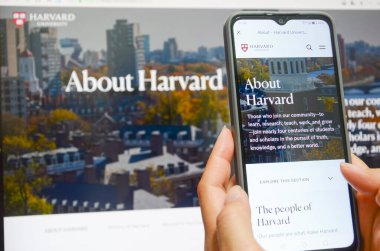 Jiangmen, Guangdong, Çin-22 Nisan 2025: Çinli kadın Harvard Üniversitesi haberlerini izlemek için akıllı telefon kullanıyor. Harvard, Trump yönetimini akademik politikalara yönelik uyarıların ardından, akademik politikaları etkileme amaçlı finansman durdurma tehditleri nedeniyle 21 Nisan 'da dava etti.