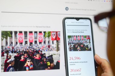 Jiangmen, Guangdong, Çin-22 Nisan 2025: Çinli kadın Harvard Üniversitesi haberlerini izlemek için akıllı telefon kullanıyor. Harvard, Trump yönetimini akademik politikalara yönelik uyarıların ardından, akademik politikaları etkileme amaçlı finansman durdurma tehditleri nedeniyle 21 Nisan 'da dava etti.
