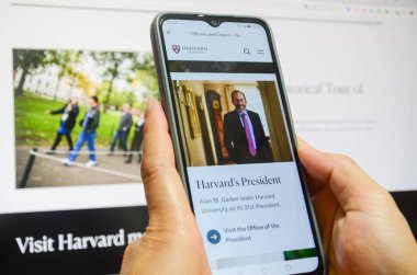 Jiangmen, Guangdong, Çin-22 Nisan 2025: Çinli kadın Harvard Üniversitesi haberlerini izlemek için akıllı telefon kullanıyor. Harvard, Trump yönetimini akademik politikalara yönelik uyarıların ardından, akademik politikaları etkileme amaçlı finansman durdurma tehditleri nedeniyle 21 Nisan 'da dava etti.