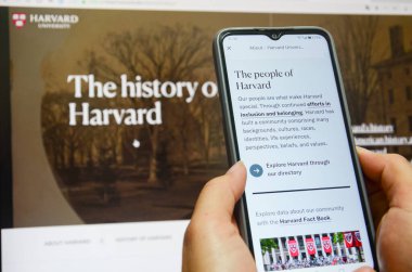 Jiangmen, Guangdong, Çin-22 Nisan 2025: Çinli kadın Harvard Üniversitesi haberlerini izlemek için akıllı telefon kullanıyor. Harvard, Trump yönetimini akademik politikalara yönelik uyarıların ardından, akademik politikaları etkileme amaçlı finansman durdurma tehditleri nedeniyle 21 Nisan 'da dava etti.
