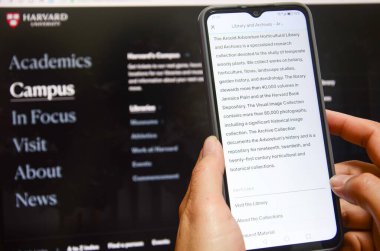 Jiangmen, Guangdong, Çin-22 Nisan 2025: Çinli kadın Harvard Üniversitesi haberlerini izlemek için akıllı telefon kullanıyor. Harvard, Trump yönetimini akademik politikalara yönelik uyarıların ardından, akademik politikaları etkileme amaçlı finansman durdurma tehditleri nedeniyle 21 Nisan 'da dava etti.