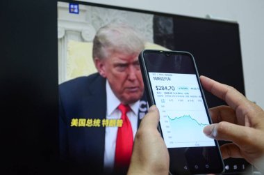 Jingmen, Guangdong, Çin 6 Haziran 2025. İnsanlar Tesla hakkındaki haberleri izlemek için akıllı telefon kullanıyor. 5 Haziran 'da (yerel saatle), Tesla' nın hisse senedi fiyatı CEO Elon Musk ile ABD Başkanı Trump arasındaki gerginliğin artması sonrasında% 14,26 oranında düştü. CNN haberi