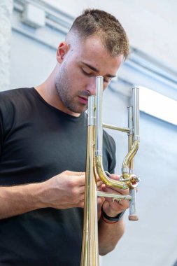 Brass müzik aleti Luthier atölyede bir F / Bb trombonunu tamir ediyor.