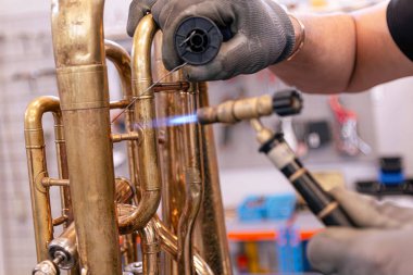 Bir tuba parçasını kaynak yapan pirinç müzik aletlerinin tamircisiyim.