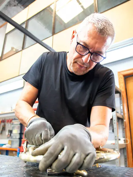 Müzikal bir enstrüman tamircisinin yakın plan çekimi. Luthier mağazasında tamir edilmiş bir Fransız kornasını cilalıyor.