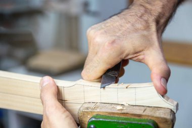 Luthier atölyesinde vihuela boynu oyuyor. Ellerini yaklaştır..