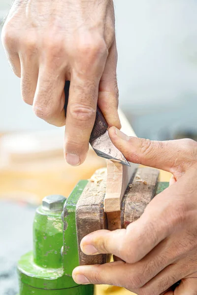 vertical shot luthier carving vihuela headstock in his workshop. close up of his hands