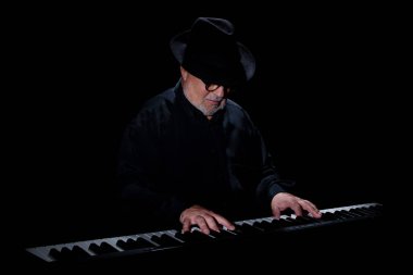 Beyaz sakallı, yuvarlak gözlüklü, müzik gününde müzik yapan, el yapımı Mısır flütü takmış siyah bir piyanonun önünde şapka takan yaşlı bir yetişkin. Siyah arka plan. Alçak tuş