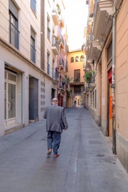 Valencia, İspanya - 19 Kasım 2023: İspanya 'da Valencia' nın tarihi merkezinde yoldan geçen biri var. Güneşli bir günde arka planda Portal de Valldigna.