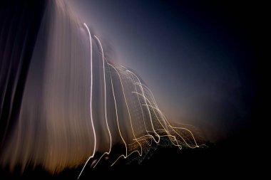 Işık çağlayanı. IŞM. Kasıtlı kamera hareketi renkli ışıklarla soyut siluetler oluşturuyor.